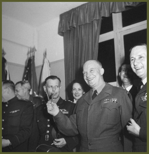 Eisenhower makes V for victory with surrender pens, German and U.S. pen at right, Russian at left