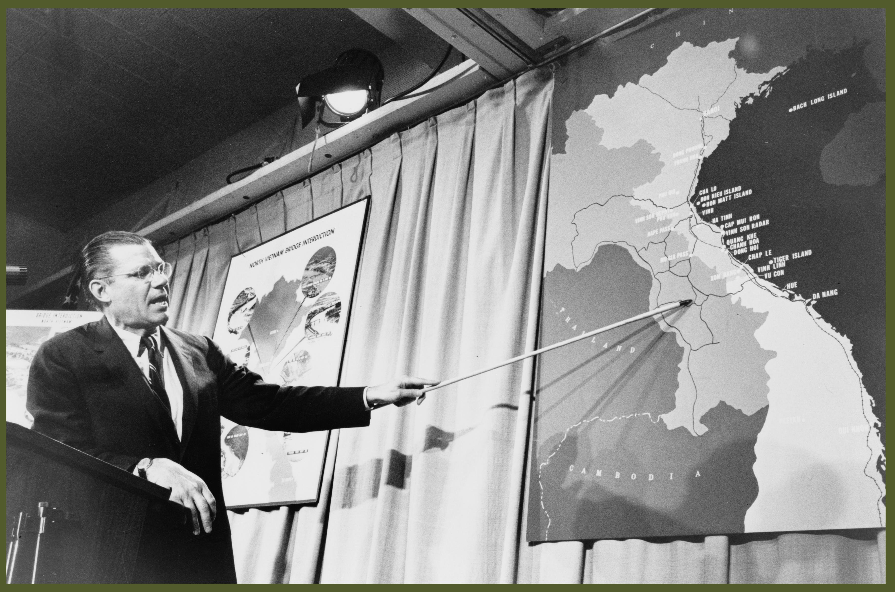 Secretary of Defense Robert McNamara pointing to a map of Vietnam at a press conference in April 1965